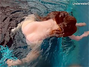 red-haired Simonna showcasing her figure underwater